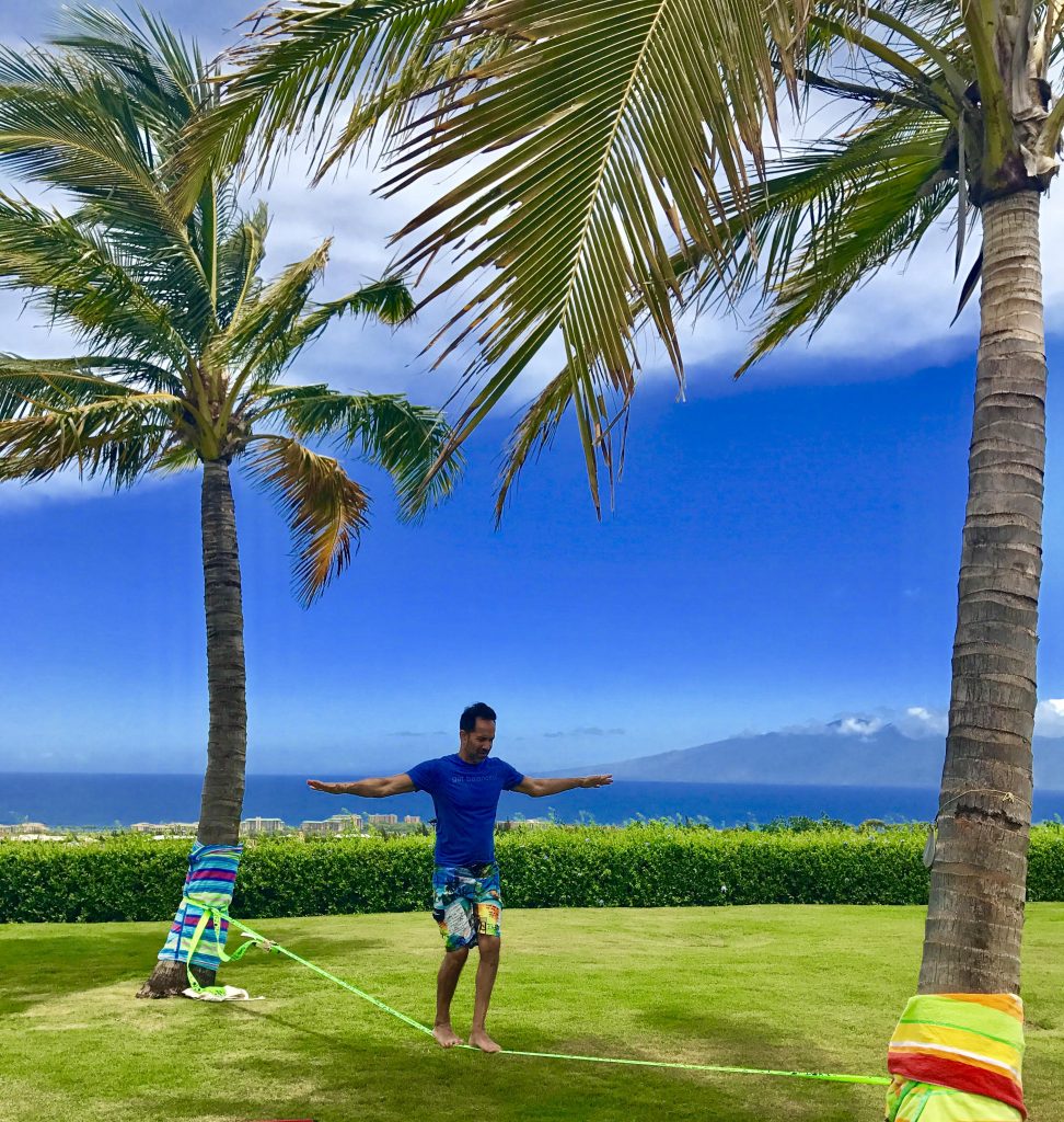Man on slackline, part of his personal trainer to go program, in tropical setting.